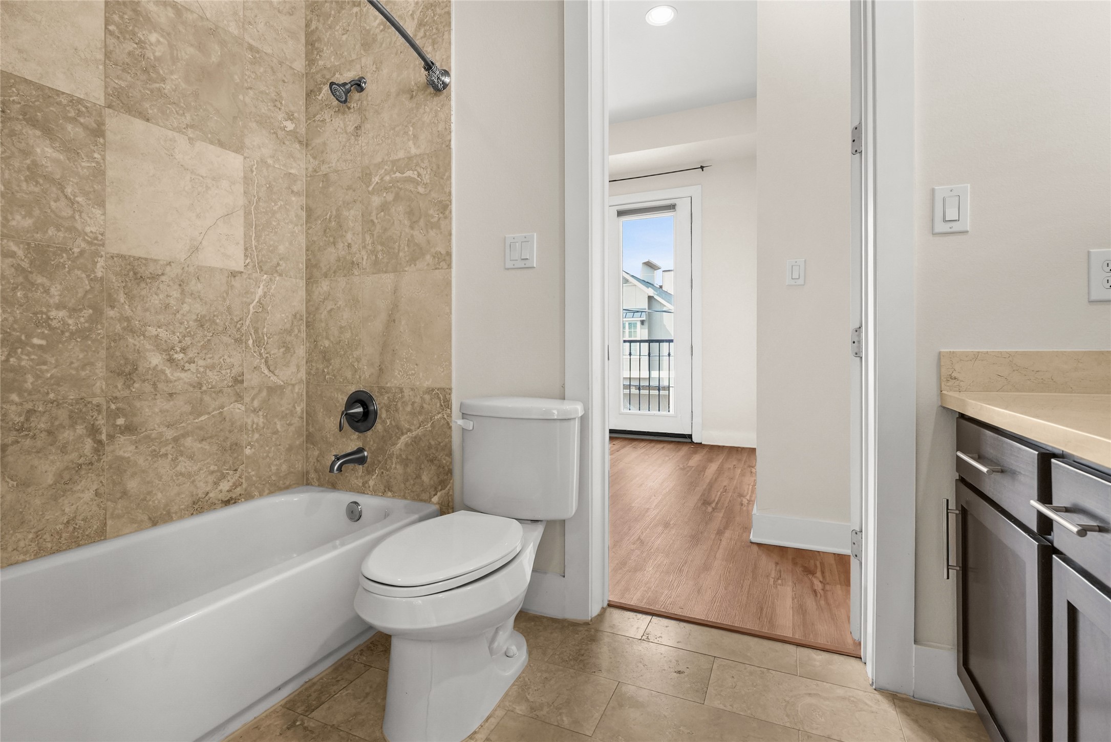4409 Schuler Street, Unit A Houston, TX 77007 - Photo 26 of 33 This bathroom, shared by the secondary bedrooms, offers rich dark cabinets, bright countertops, and a tub/shower accented with travertine tile.