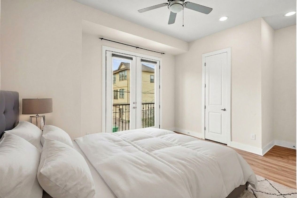 4409 Schuler Street, Unit A Houston, TX 77007 - Photo 29 of 33 Bedroom 3 features wood-look flooring and glass-paneled French doors opening to a private balcony overlooking the driveway.**This room has been virtually staged.