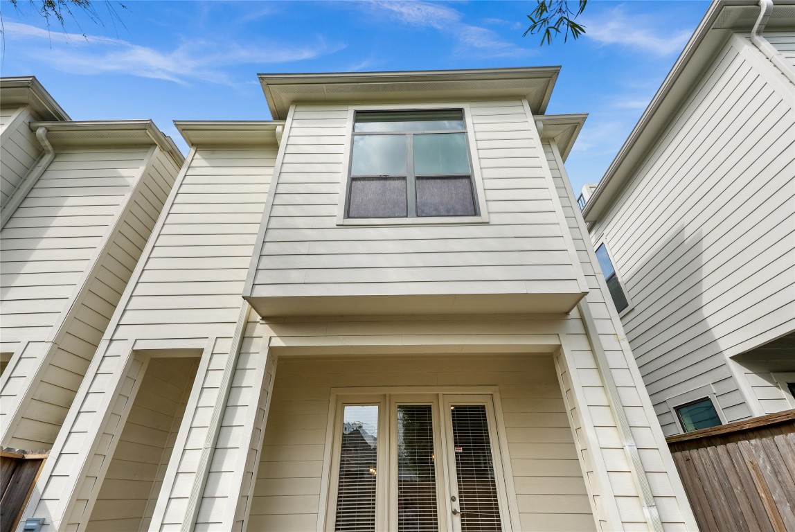 4409 Schuler Street, Unit A Houston, TX 77007 - Photo 7 of 33 Exterior features neutral-toned horizontal siding, large windows, and a private entryway tucked beneath the second-story overhang.