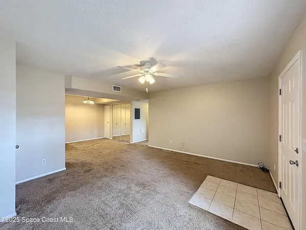 an empty room with a ceiling fan and window