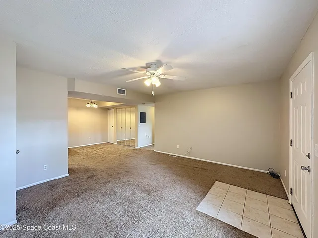 an empty room with a ceiling fan and window