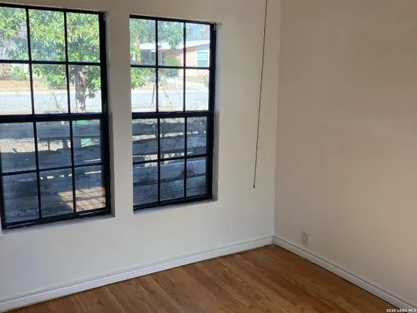 an empty room with wooden floor and windows