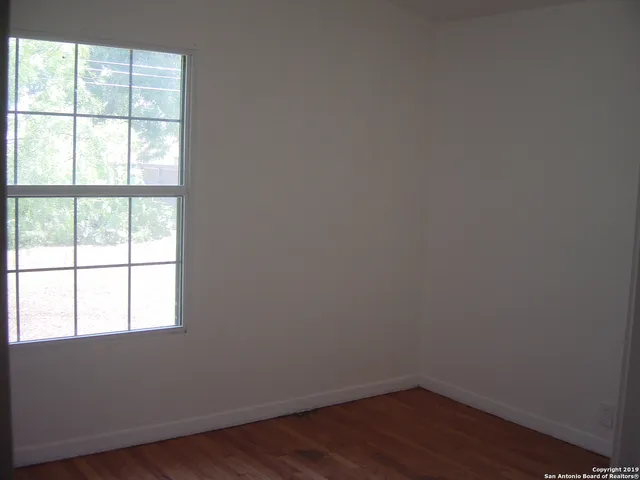 a view of a small space with wooden floor and a window