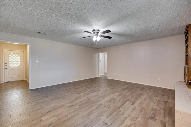 a view of an empty room with a window and wooden floor
