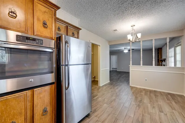 a kitchen with stainless steel appliances a refrigerator and a hard wood floor