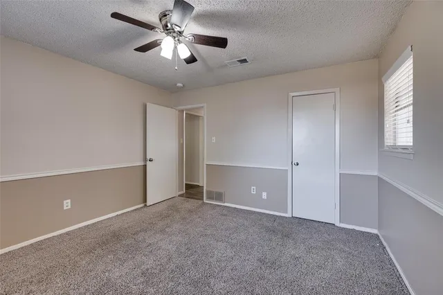 a view of an empty room and chandelier fan