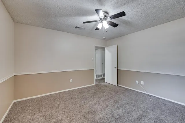 a view of an empty room with chandelier fan