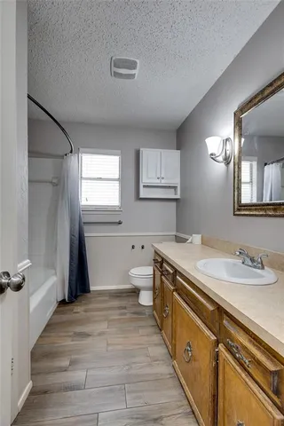 a spacious bathroom with a granite countertop sink a toilet a mirror and a window