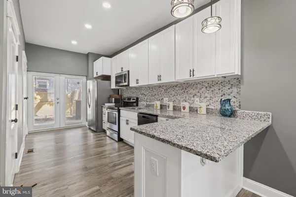 a kitchen with stainless steel appliances granite countertop a sink dishwasher a refrigerator and a stove with wooden floor