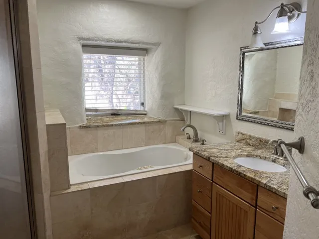 a bathroom with a granite countertop sink mirror and a bathtub