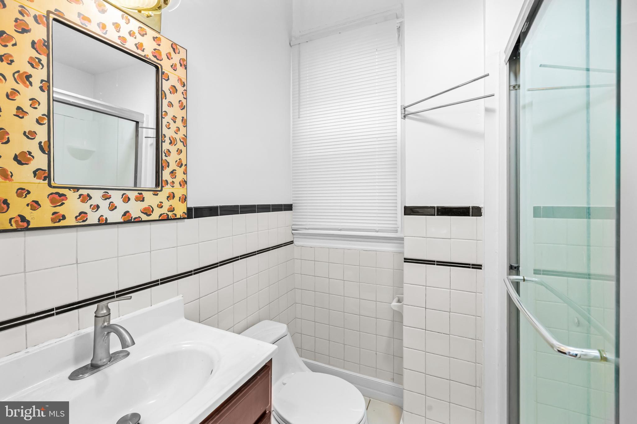 1021 Columbia Road Northwest Washington, DC 20001 - Photo 12 of 55 a bathroom with a sink a mirror and shower