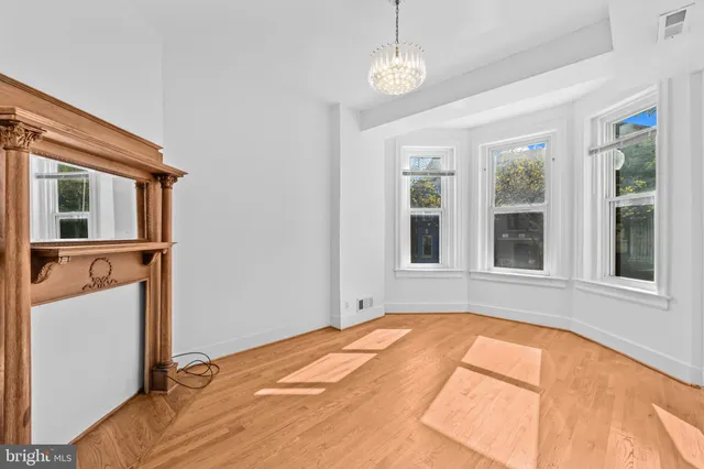 a view of an empty room with a window and chandelier