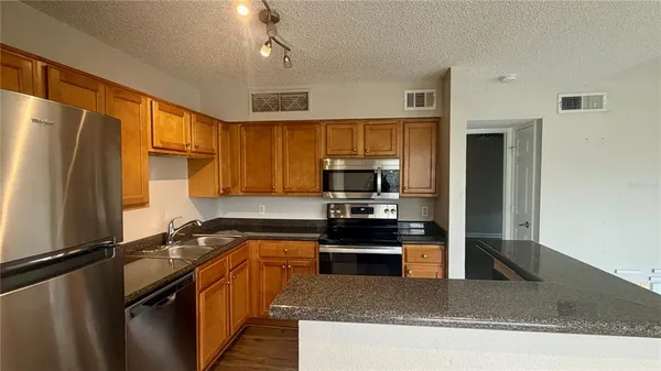 a kitchen with stainless steel appliances granite countertop a refrigerator a stove top oven a sink and dishwasher