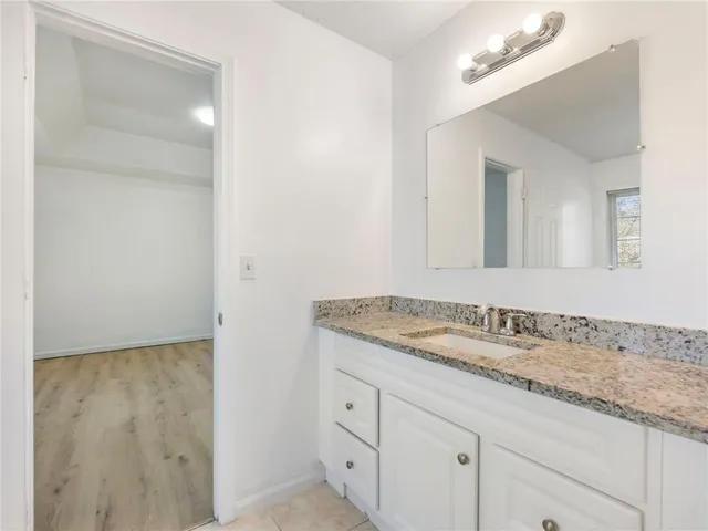 a bathroom with a granite countertop sink and a mirror