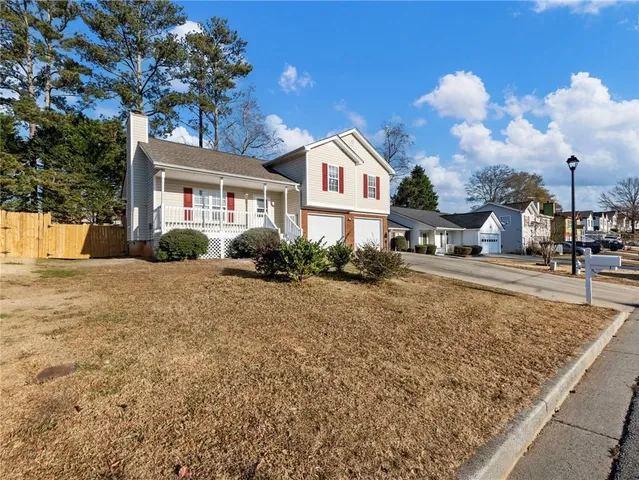 a view of a white house next to a yard with big trees