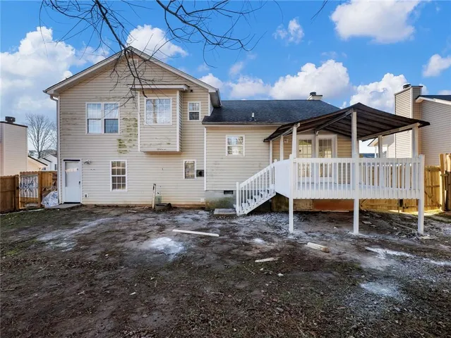a white house that has a small yard and large trees