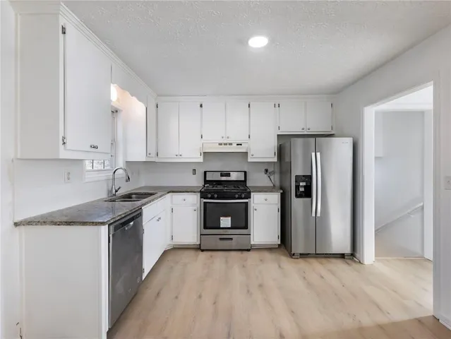 a kitchen with stainless steel appliances granite countertop a refrigerator and a stove top oven