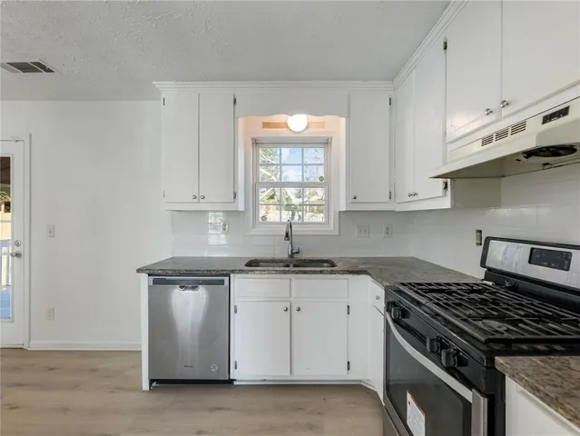 a kitchen with granite countertop a sink stove and cabinets
