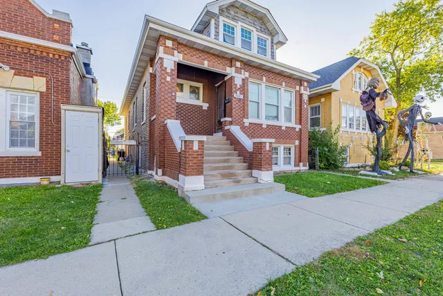 a front view of a house with a yard and potted plants