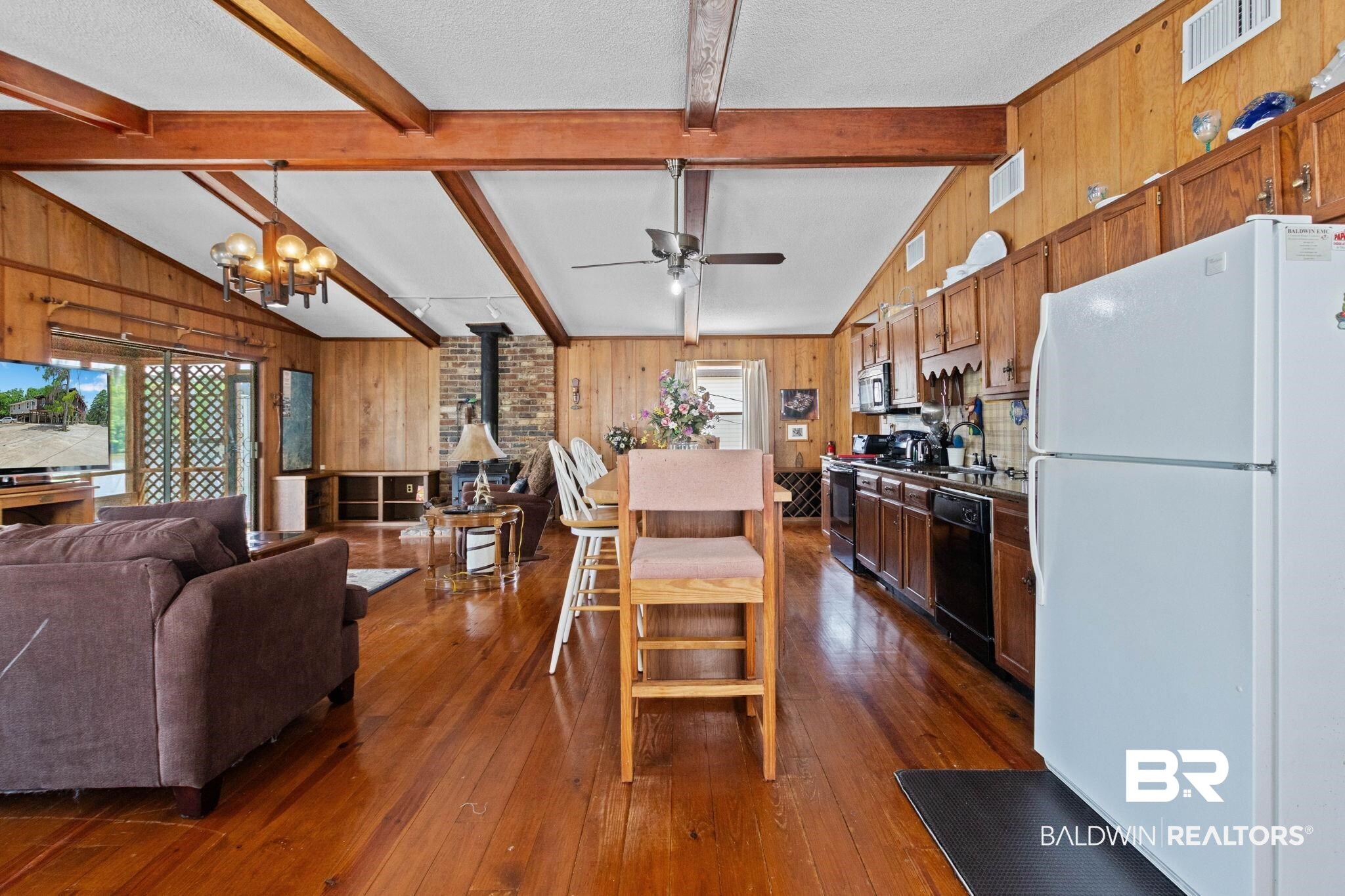 8153 Bryant's Lndg Road Stockton, AL 36579 - Photo 26 of 87 Open-concept living space featuring wood-finish flooring, exposed wood beams, and paneled wood walls