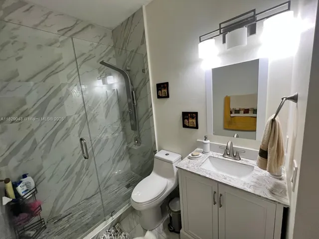 a bathroom with a granite countertop sink toilet and shower