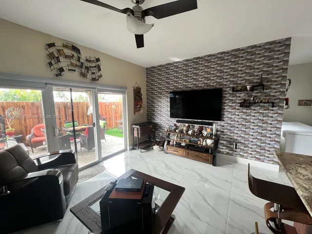 a living room with furniture a flat screen tv and a large window