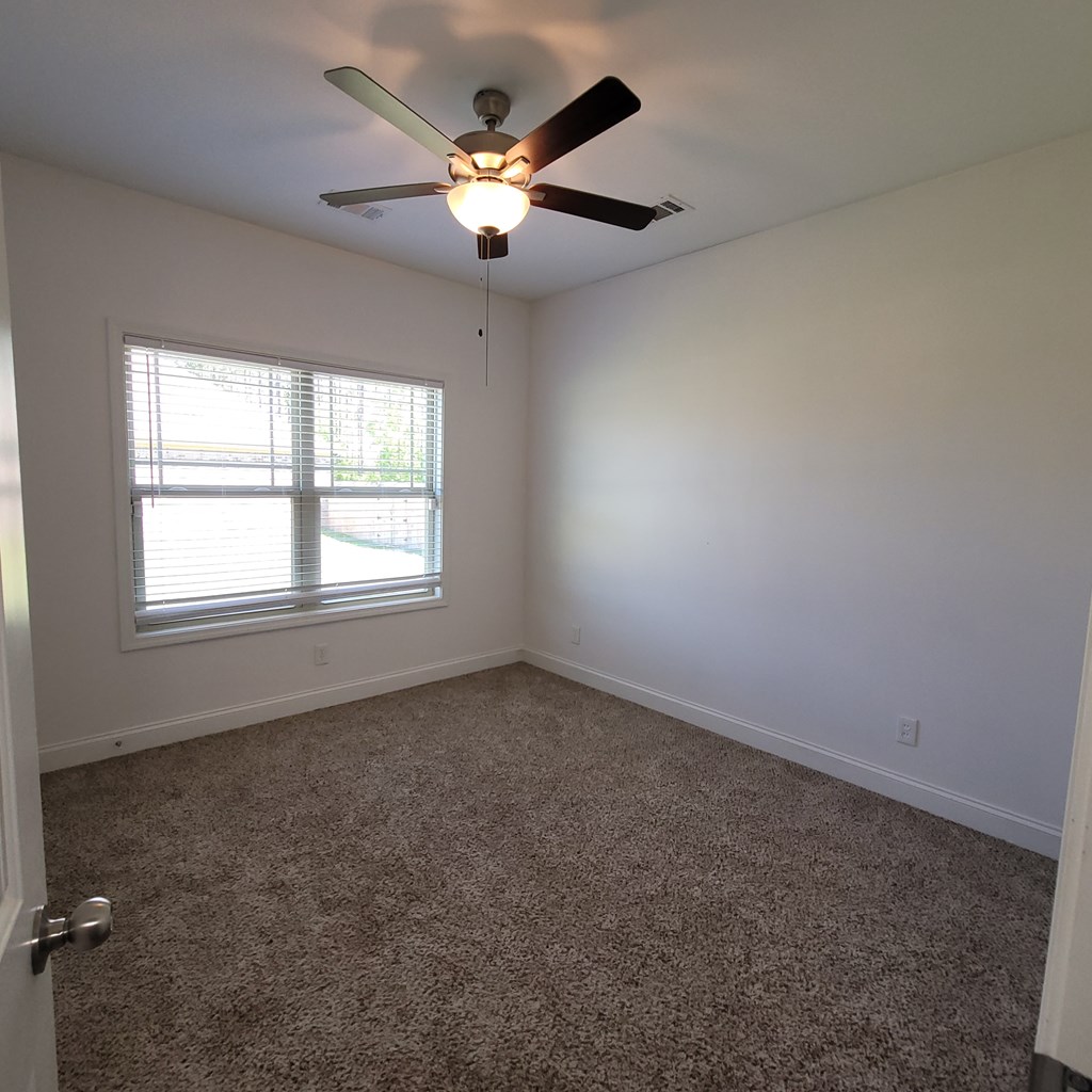 19 Fast Lane Seale, AL 36875 - Photo 12 of 18 an empty room with a chandelier fan and windows