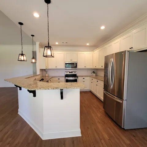a kitchen with kitchen island a counter top a refrigerator a sink and wooden floor