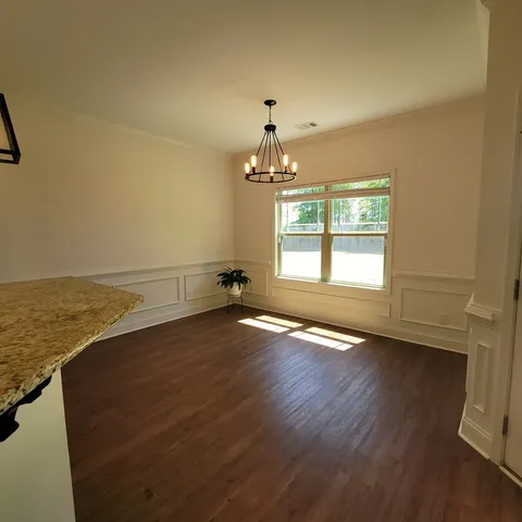 an empty room with wooden floor chandelier and windows