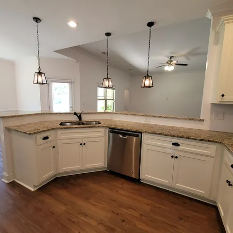 a kitchen with a sink window and wooden floor