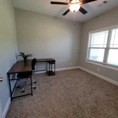 an empty room with windows and ceiling fan