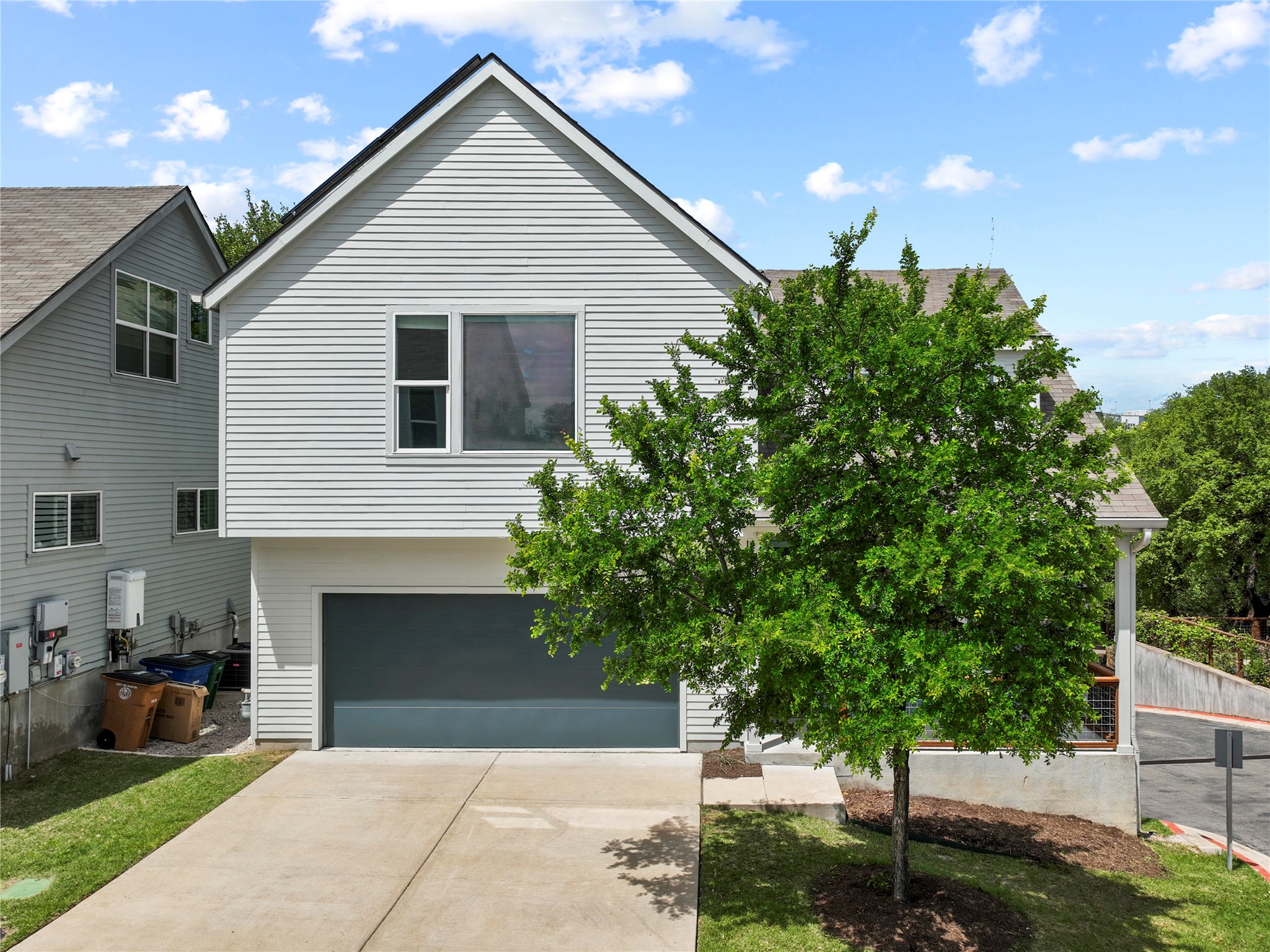 The property features light-colored siding, a dark garage door, and a concrete driveway