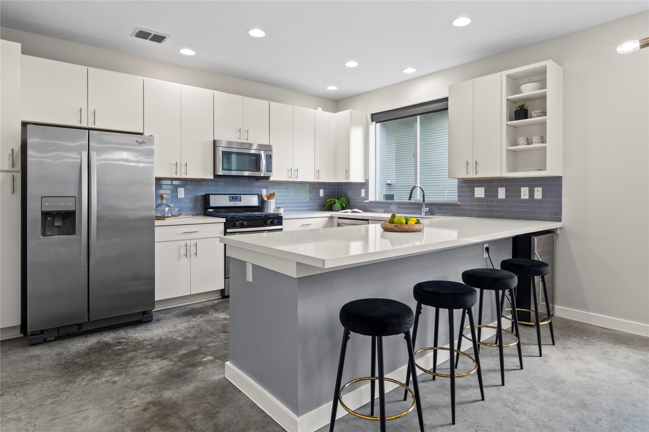 3001 Del Curto Road, Unit 35 Austin, TX 78704 - Photo 7 of 22 The kitchen features an island with a light-colored countertop, white cabinetry, a stainless steel refrigerator, and a stainless steel microwave