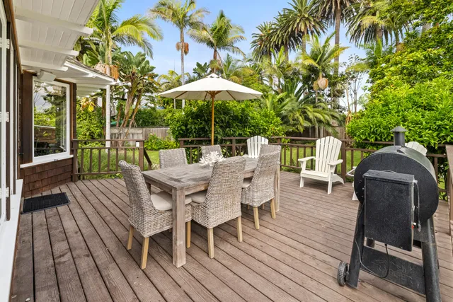 a view of a roof deck with table and chairs under an umbrella with wooden floor