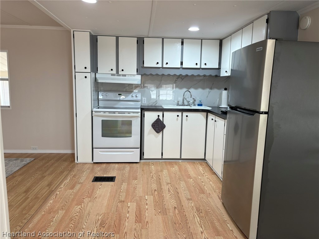 7938 Elliott Road Sebring, FL 33876 - Photo 7 of 20 a kitchen with granite countertop a refrigerator sink and cabinets