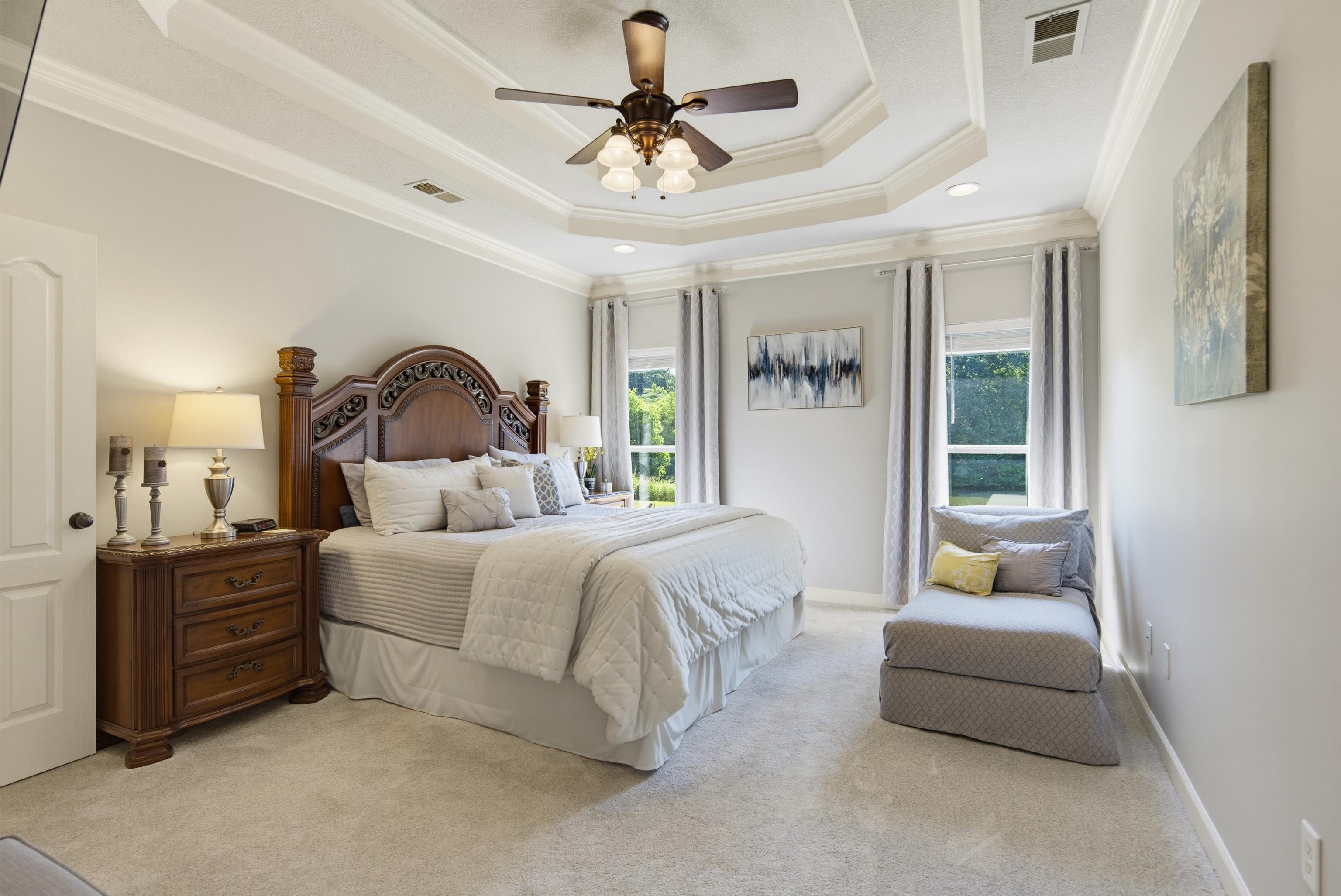 243 Hayes Road Munford, TN 38058 - Photo 13 of 25 Spacious room featuring a tiered tray ceiling with crown molding, a ceiling fan with integrated lighting, light grey walls, and light-colored carpeting with views of the lake.