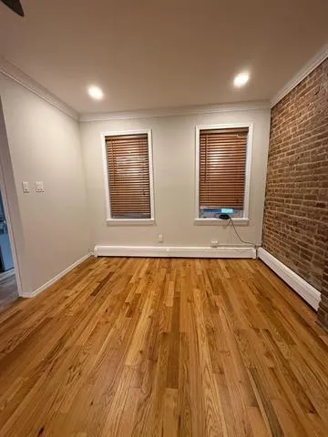 a view of an empty room with wooden floor and windows