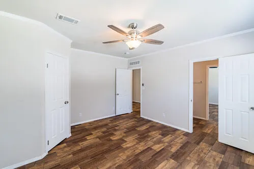 an empty room with windows and a chandelier fan