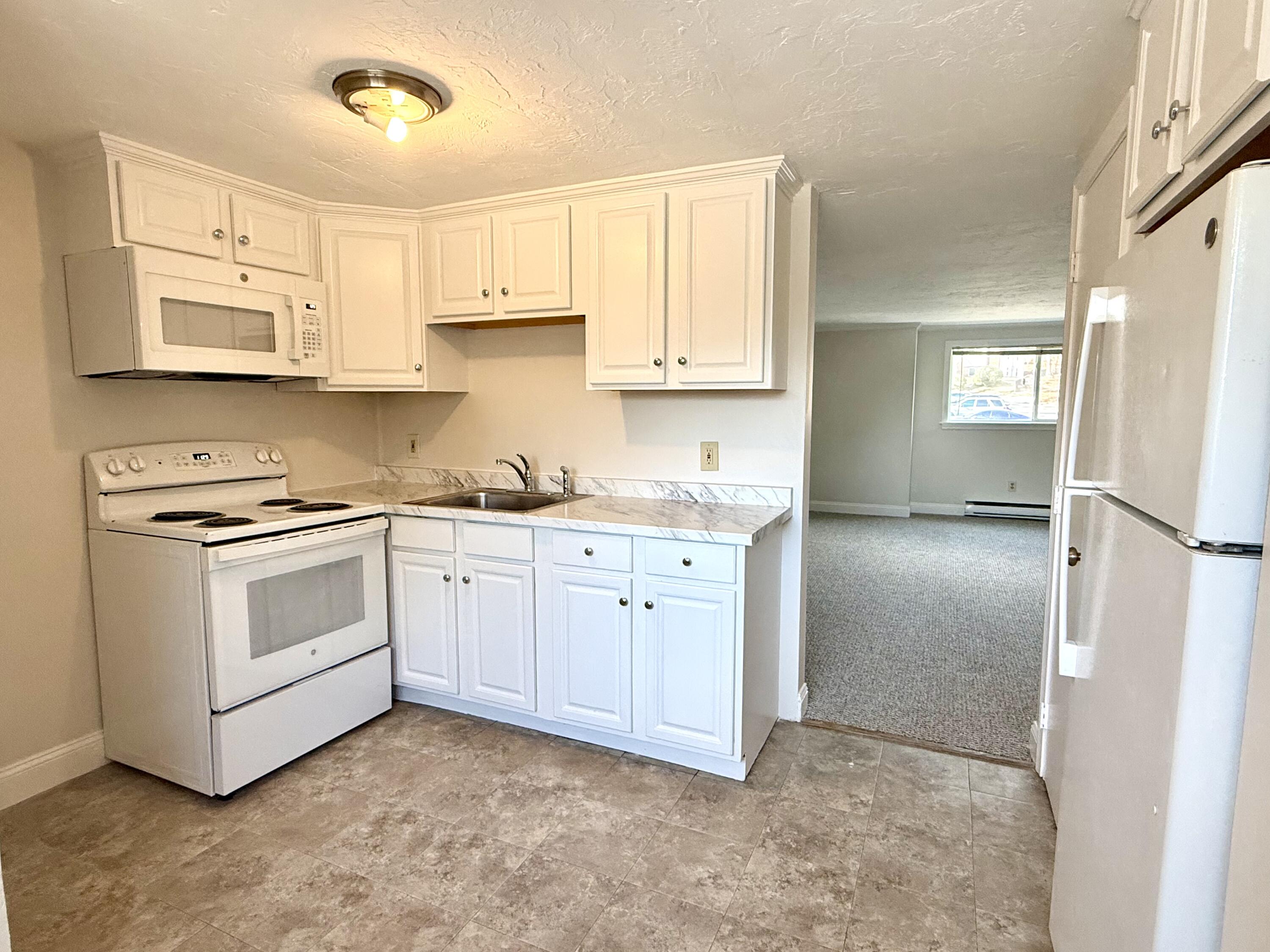 a kitchen with white cabinets and white appliances