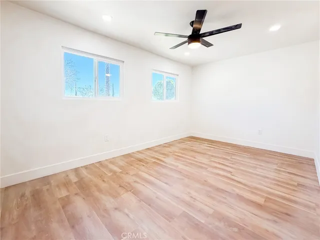 a view of a room with wooden floor and a ceiling fan