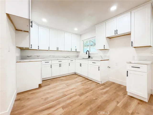 a kitchen with stainless steel appliances granite countertop a stove a sink and white cabinets