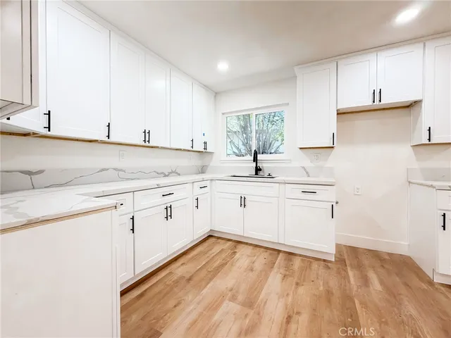 a kitchen with granite countertop white cabinets white appliances and sink
