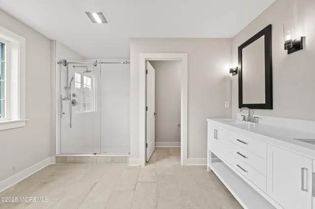 a spacious bathroom with a double vanity sink a mirror and a shower