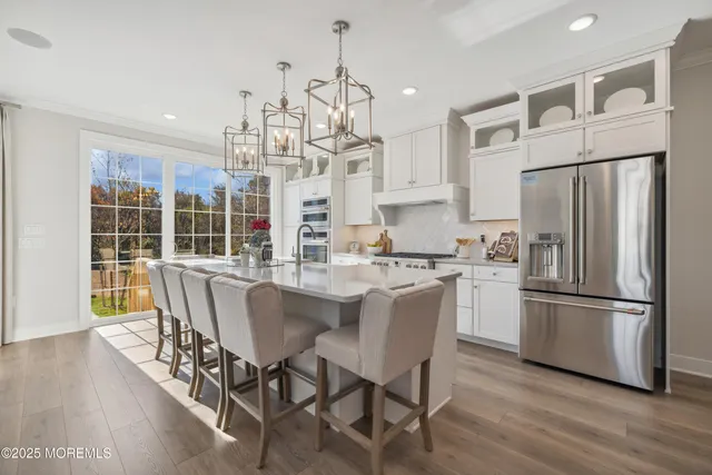 a kitchen with stainless steel appliances granite countertop a dining table chairs refrigerator and wooden floor