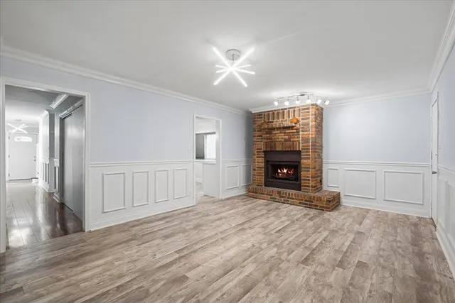 a view of an empty room with wooden floor fireplace and a window