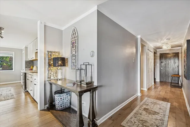 a view of front door with hallway and wooden floor