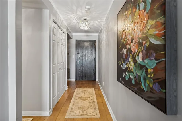 a view of a hallway with wooden floor and a chandelier