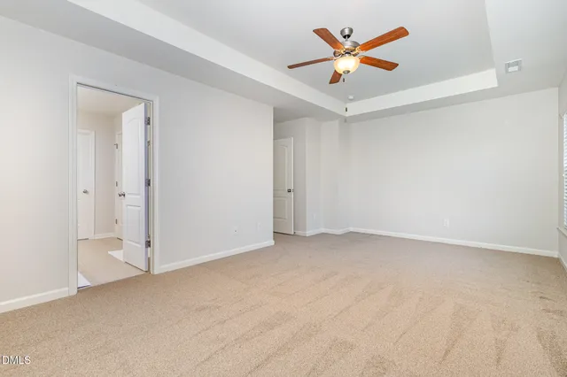 a spacious bedroom with a bed a dresser and a large window
