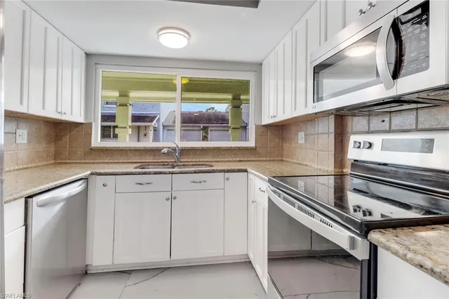 a kitchen with granite countertop stainless steel appliances a sink stove and cabinets