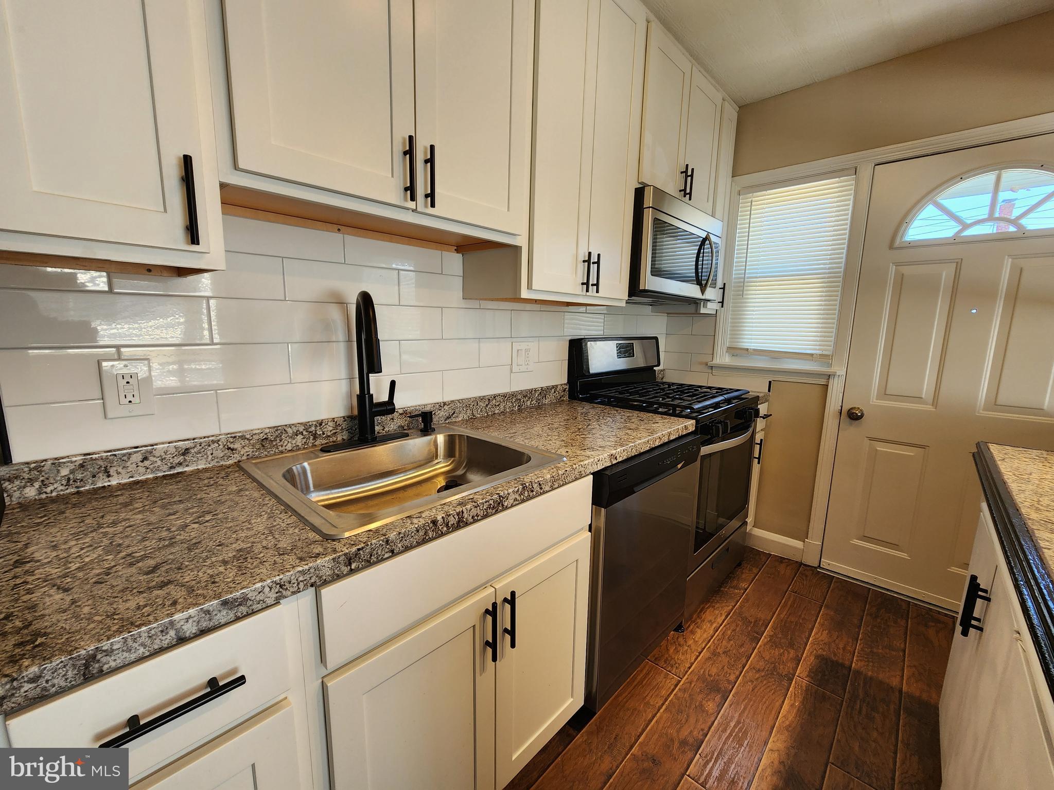 1925 Ewald Avenue Baltimore, MD 21222 - Photo 9 of 29 a kitchen with granite countertop a sink stainless steel appliances white cabinets and a counter top space